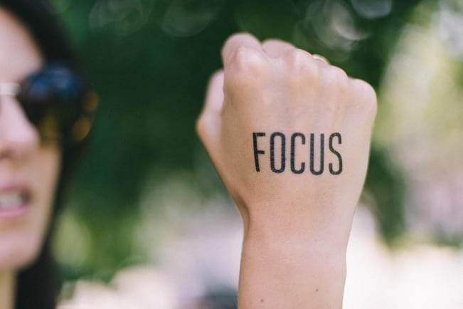 A close-up of a hand with the word “focus” written on the back